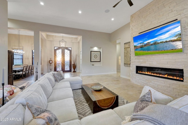 living room featuring ceiling fan with notable chandelier, french doors, and a fireplace