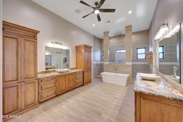 bathroom with tile walls, ceiling fan, independent shower and bath, and vanity