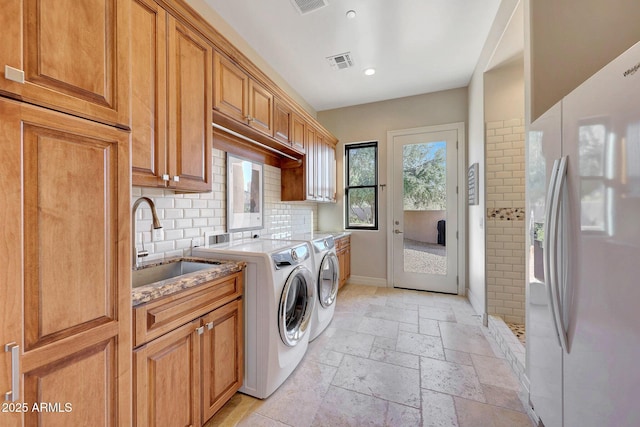 washroom featuring sink, separate washer and dryer, and cabinets