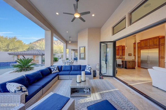 view of patio with ceiling fan, an outdoor living space, and a mountain view