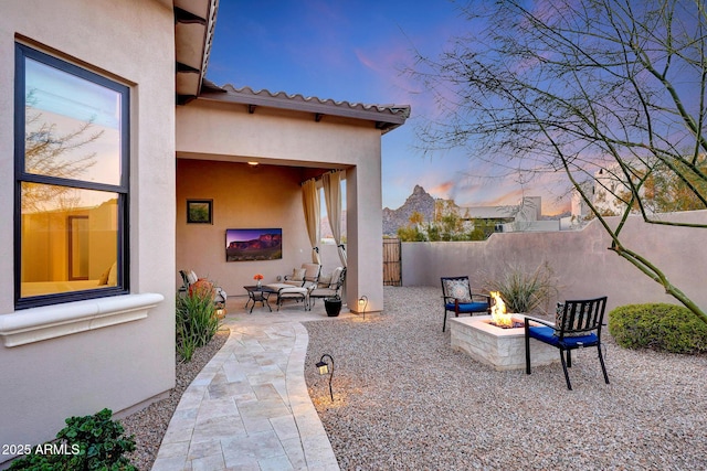 patio terrace at dusk with an outdoor living space with a fire pit