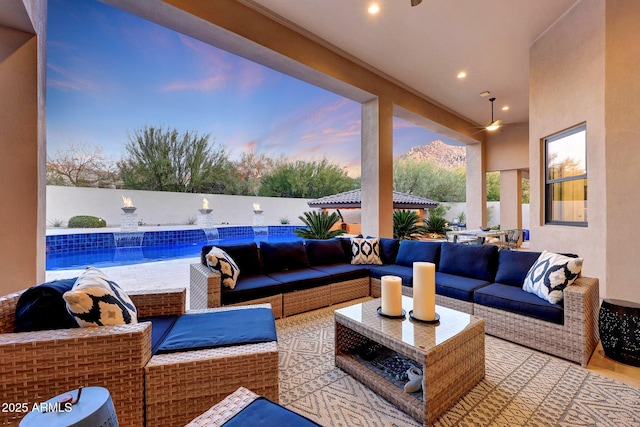 patio terrace at dusk featuring a fenced in pool and an outdoor living space