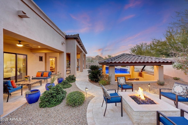 patio terrace at dusk with an outdoor living space with a fire pit