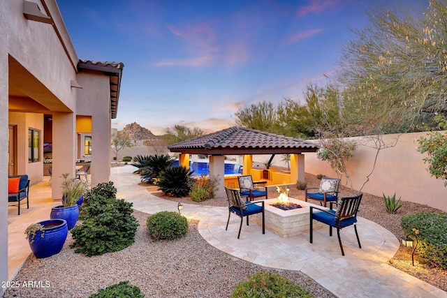 patio terrace at dusk featuring a fire pit and a gazebo