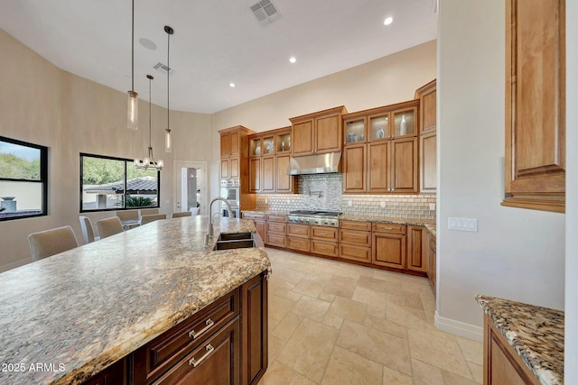 kitchen with sink, decorative light fixtures, a breakfast bar area, light stone countertops, and appliances with stainless steel finishes