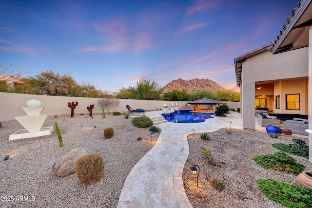 yard at dusk featuring an outdoor hangout area, a fenced in pool, a mountain view, a gazebo, and a patio area