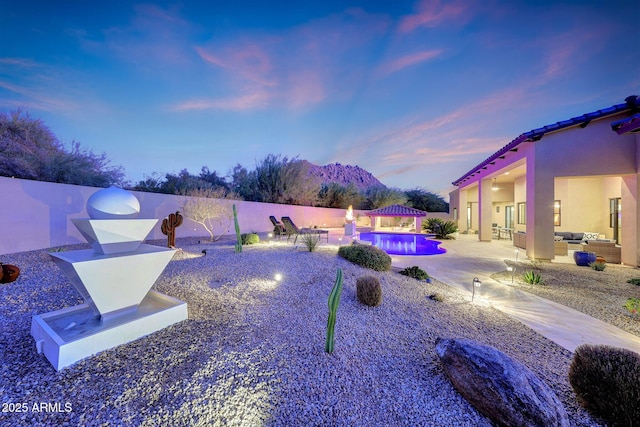 yard at dusk with a patio, a fenced in pool, and an outdoor living space