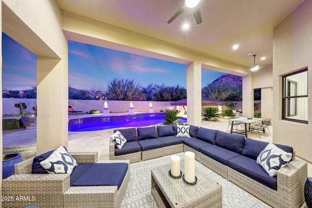 patio terrace at dusk with ceiling fan, a fenced in pool, and outdoor lounge area