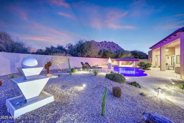 yard at dusk with a gazebo, a mountain view, a patio, and a fenced in pool