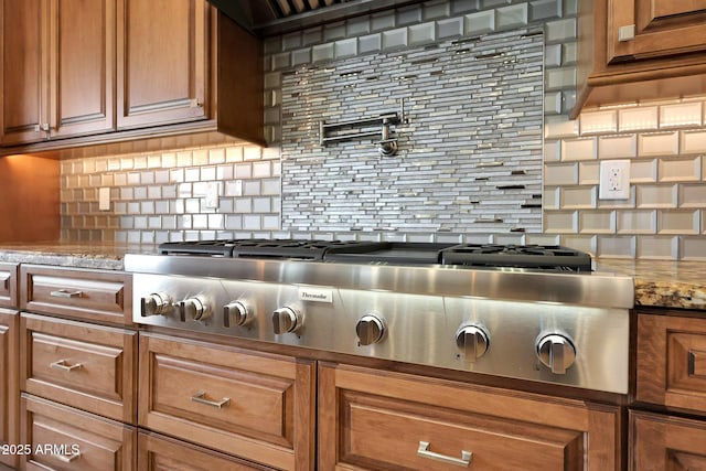 kitchen featuring stainless steel gas stovetop, tasteful backsplash, and light stone counters