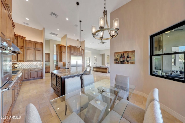 dining area featuring a towering ceiling and ceiling fan with notable chandelier