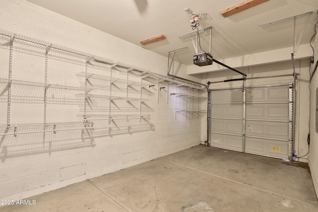 garage featuring concrete block wall and a garage door opener