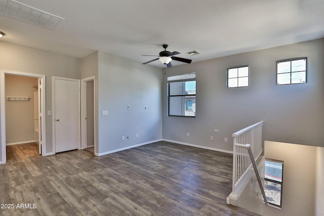 empty room featuring dark wood-type flooring, visible vents, and plenty of natural light