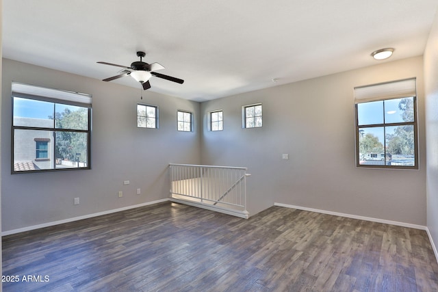 spare room with a ceiling fan, baseboards, and dark wood-style flooring