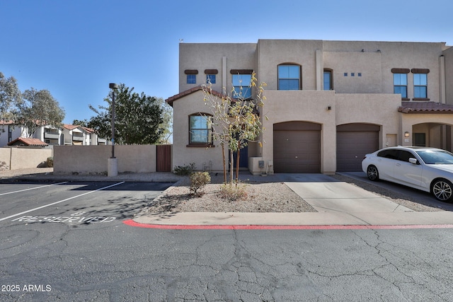 view of front of property with uncovered parking, fence, a garage, and stucco siding