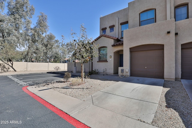 view of front of property with a garage, a tile roof, fence, and stucco siding