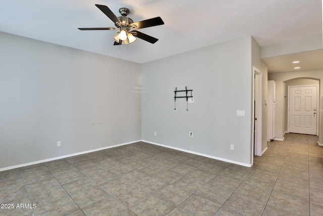 empty room with baseboards, arched walkways, a ceiling fan, tile patterned flooring, and recessed lighting