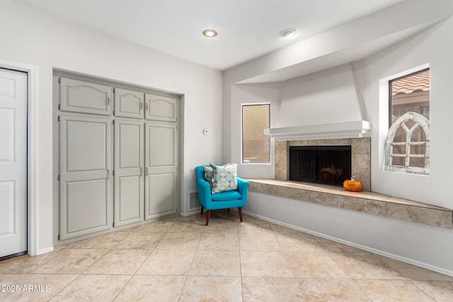 unfurnished room featuring a tiled fireplace, a wealth of natural light, and light tile patterned flooring