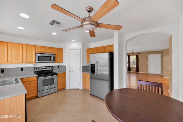 kitchen featuring arched walkways, light tile patterned floors, visible vents, appliances with stainless steel finishes, and a sink