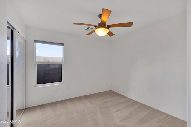 spare room featuring light carpet, visible vents, and a ceiling fan