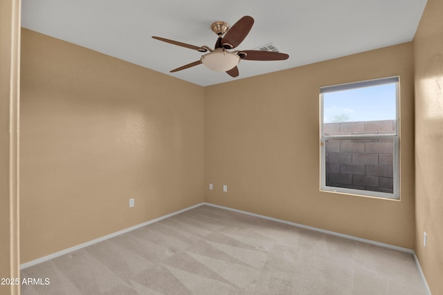 spare room with a ceiling fan, light colored carpet, visible vents, and baseboards