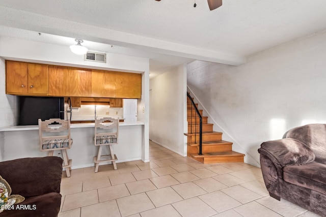 kitchen featuring beam ceiling, a kitchen breakfast bar, kitchen peninsula, a textured ceiling, and light tile patterned flooring