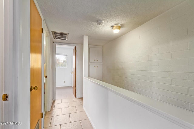 corridor with light tile patterned floors and a textured ceiling