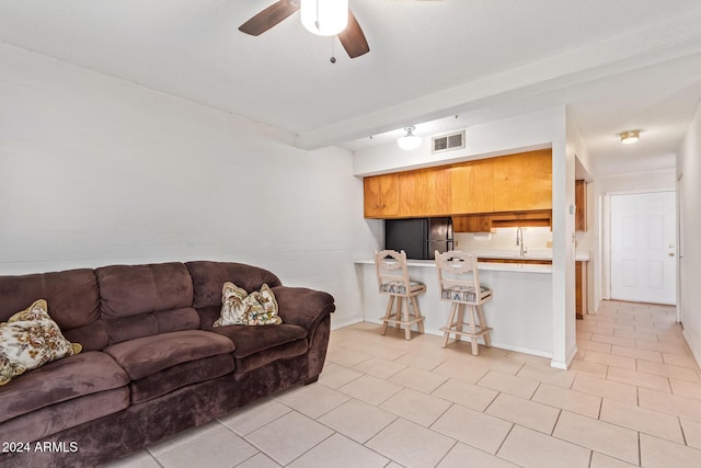 living room featuring beamed ceiling, ceiling fan, light tile patterned flooring, and sink