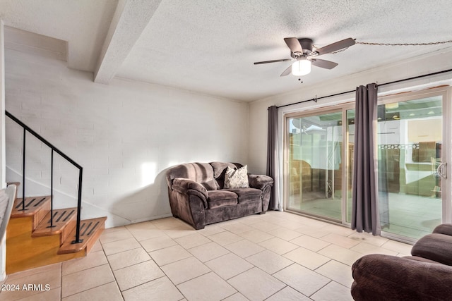 living room featuring beam ceiling, ceiling fan, light tile patterned floors, and a textured ceiling