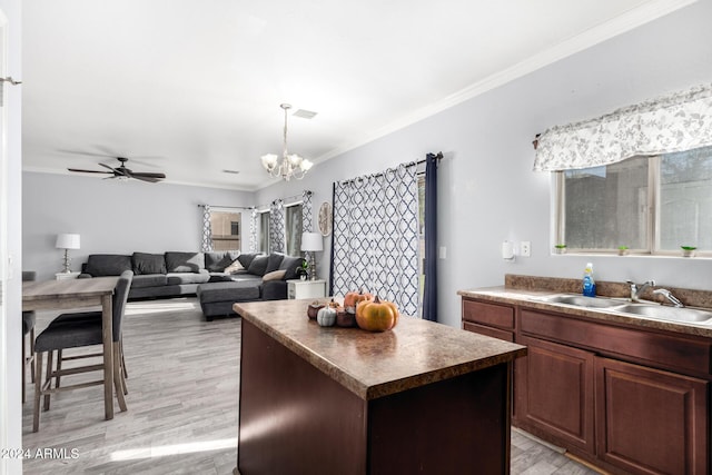 kitchen with ceiling fan with notable chandelier, sink, crown molding, light hardwood / wood-style flooring, and a kitchen island