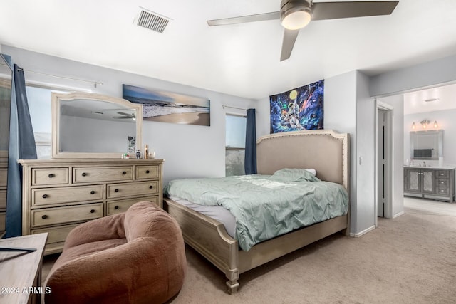 bedroom featuring connected bathroom, light carpet, and ceiling fan