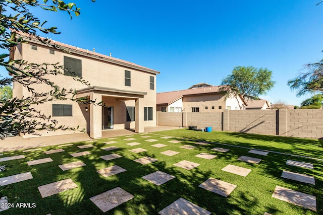 rear view of property with a lawn and a patio