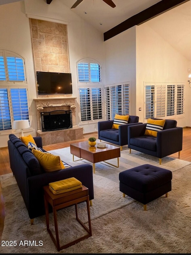 living room featuring a tile fireplace, wood-type flooring, ceiling fan, and high vaulted ceiling