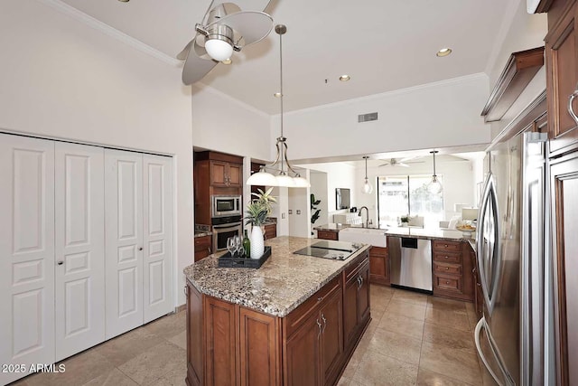 kitchen featuring ceiling fan, appliances with stainless steel finishes, decorative light fixtures, and a center island