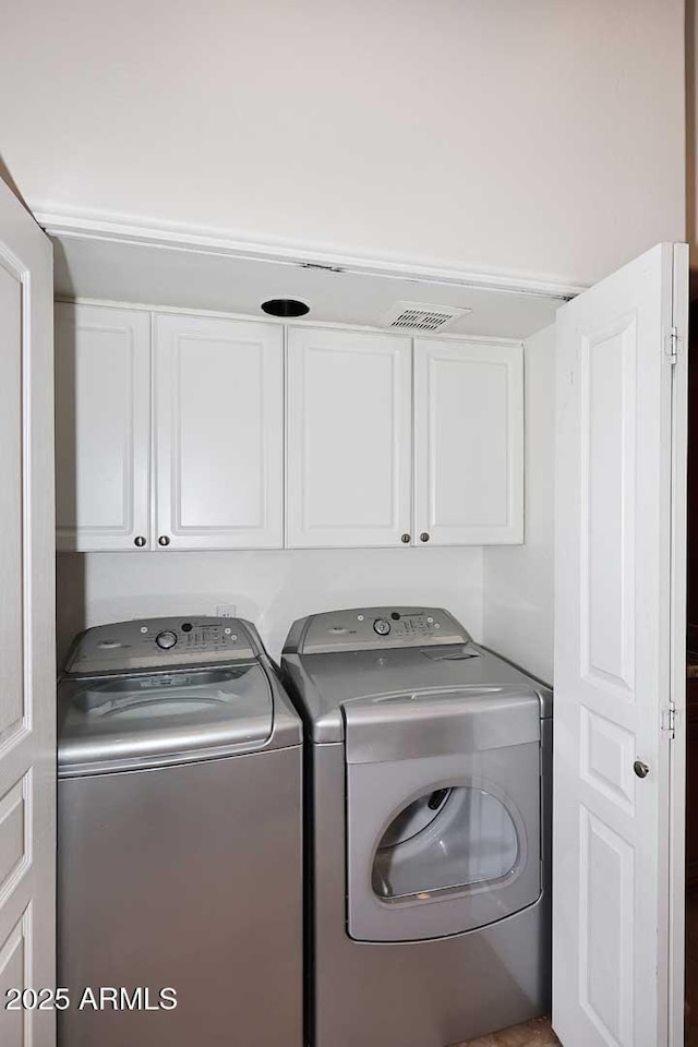 washroom with cabinets and washing machine and clothes dryer