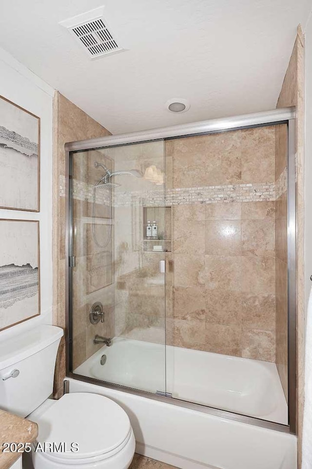 bathroom featuring toilet and combined bath / shower with glass door