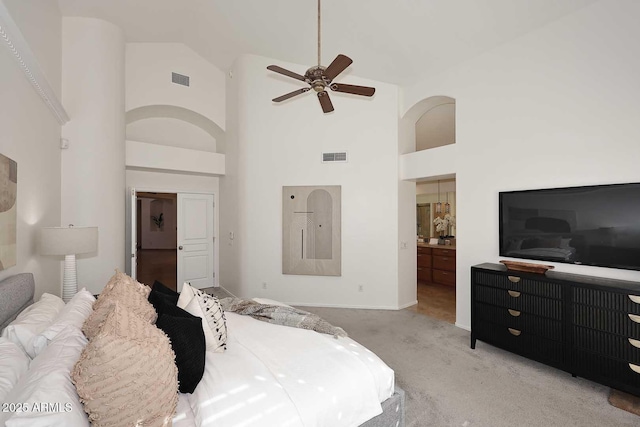 bedroom featuring high vaulted ceiling, ensuite bath, light colored carpet, and ceiling fan