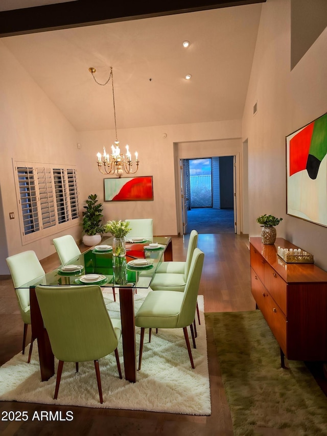 dining area featuring dark wood-type flooring, high vaulted ceiling, and an inviting chandelier