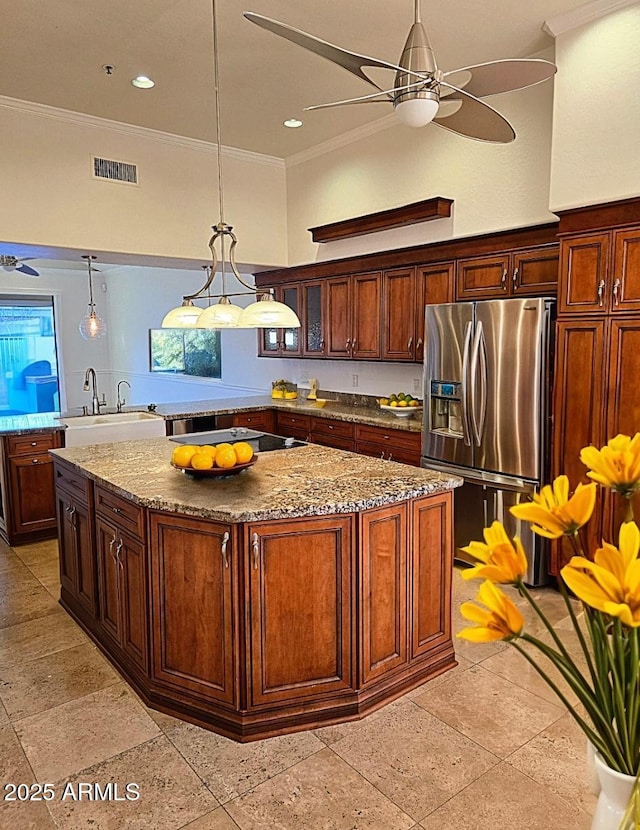 kitchen with stainless steel refrigerator with ice dispenser, sink, decorative light fixtures, a kitchen island, and ceiling fan