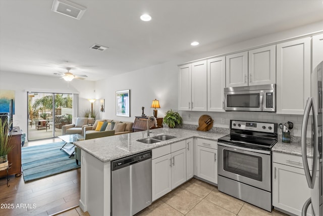 kitchen featuring white cabinets, kitchen peninsula, sink, and appliances with stainless steel finishes