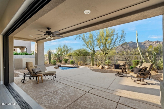view of patio with a mountain view, a fenced backyard, and ceiling fan