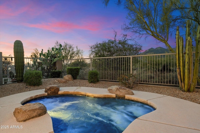 view of pool with fence and a hot tub