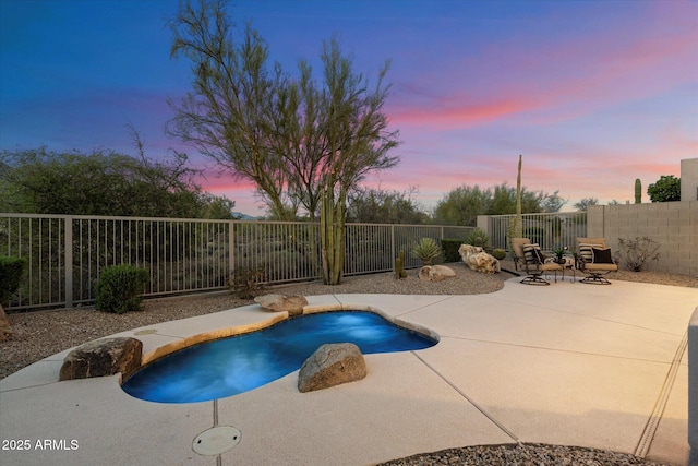 pool at dusk with a fenced backyard, a fenced in pool, and a patio