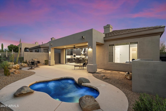 pool at dusk with fence, a fenced in pool, ceiling fan, and a patio area