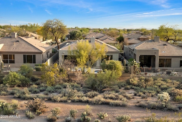 exterior space with fence, a tile roof, stucco siding, and a chimney