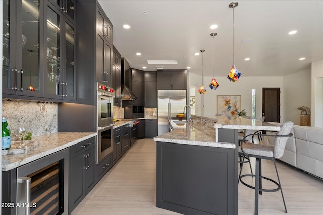 kitchen with a kitchen bar, stainless steel appliances, wine cooler, a sink, and backsplash