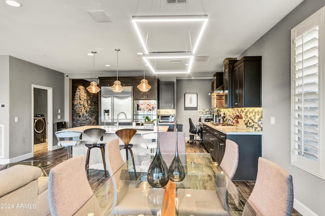 interior space featuring washer / dryer, light countertops, hanging light fixtures, and built in appliances