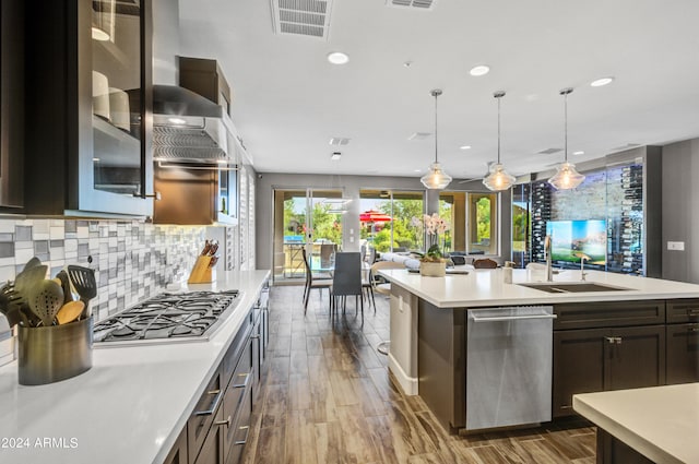 kitchen with decorative light fixtures, a center island with sink, visible vents, light countertops, and stainless steel gas stovetop