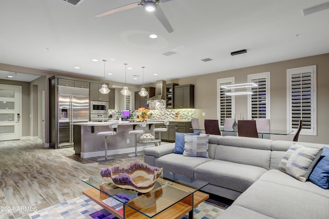 living area with light wood-type flooring, ceiling fan, visible vents, and recessed lighting