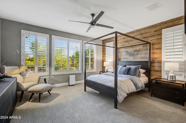 bedroom with visible vents, baseboards, ceiling fan, carpet floors, and wood walls